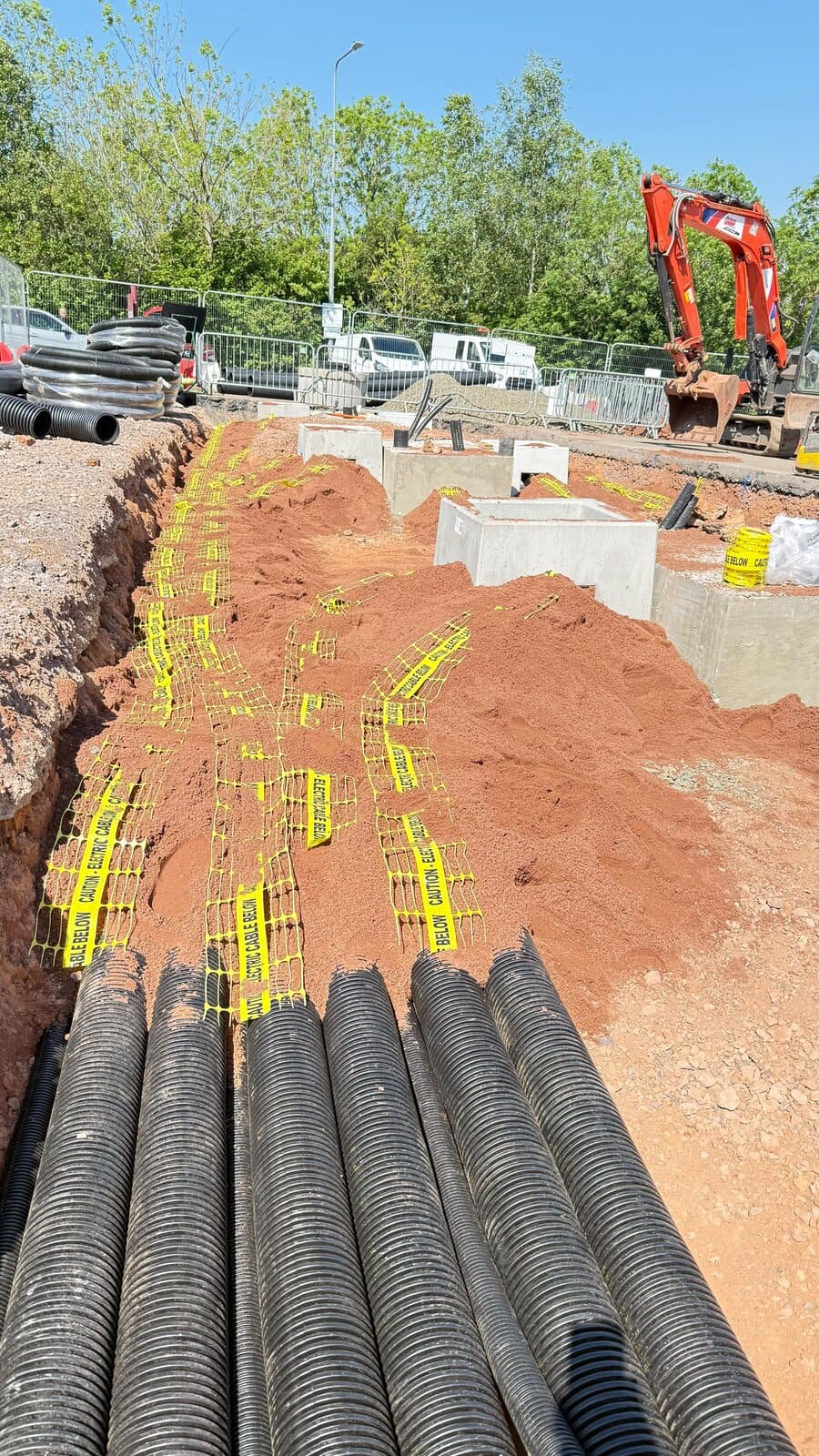 Ducts laid in the trench with warning tape run above them before backfilling