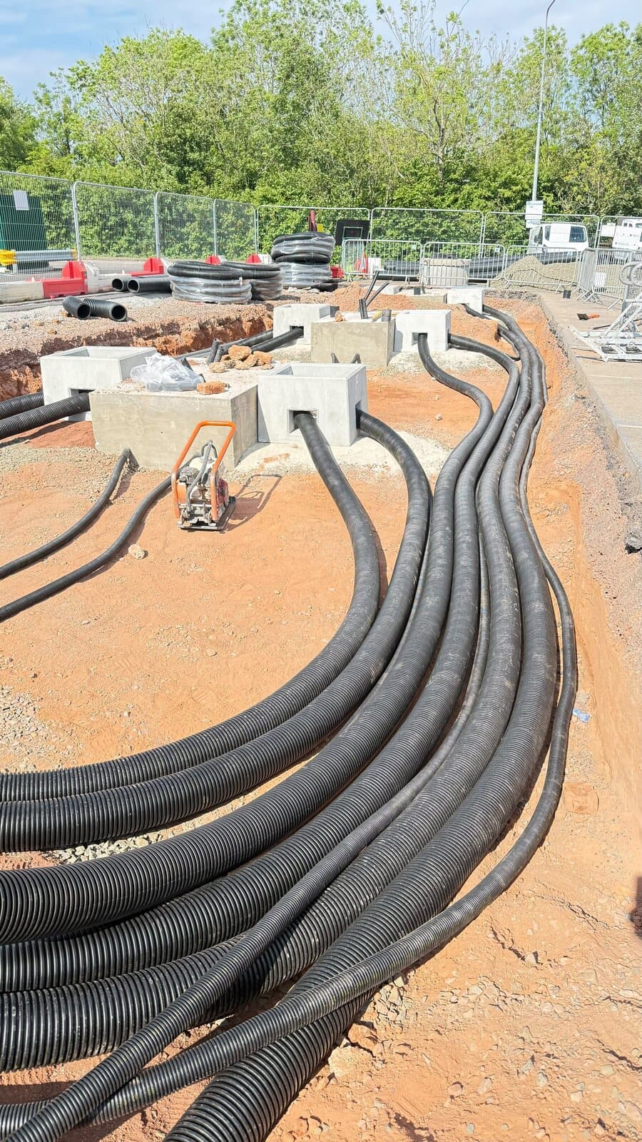 Runs of ducting swept into an open trench on site, ready for the cables to be pulled through