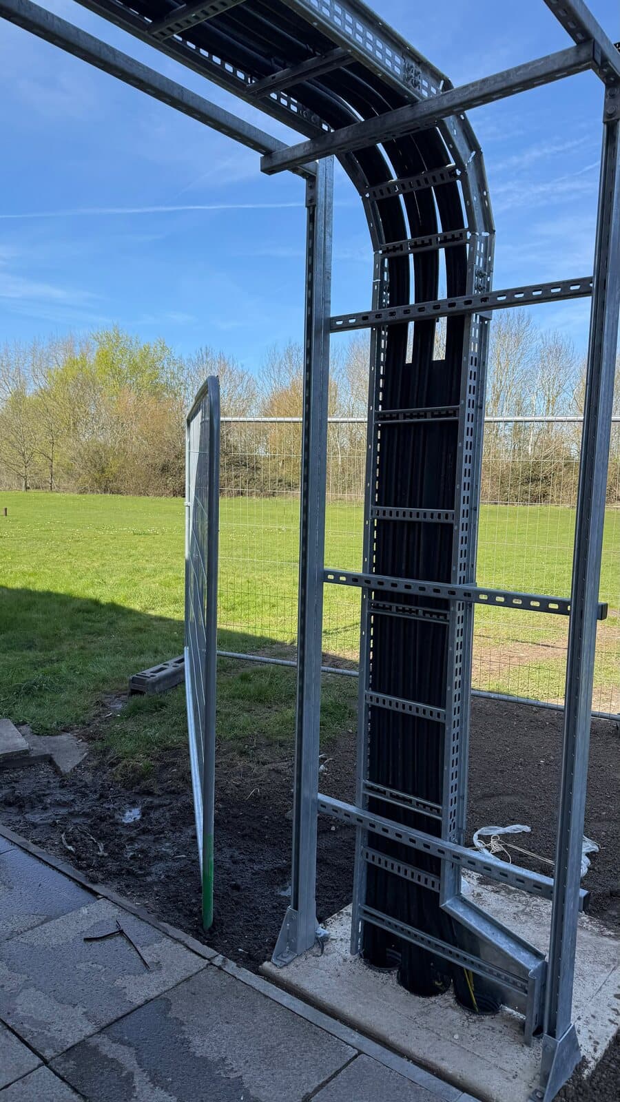Cable tray carried over a galvanised gantry frame to clear the ground below