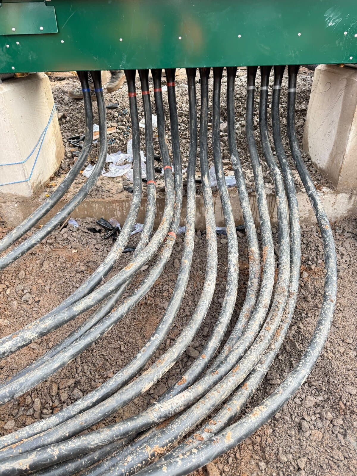Armoured cables curving up out of the ground into the base of a new feeder pillar