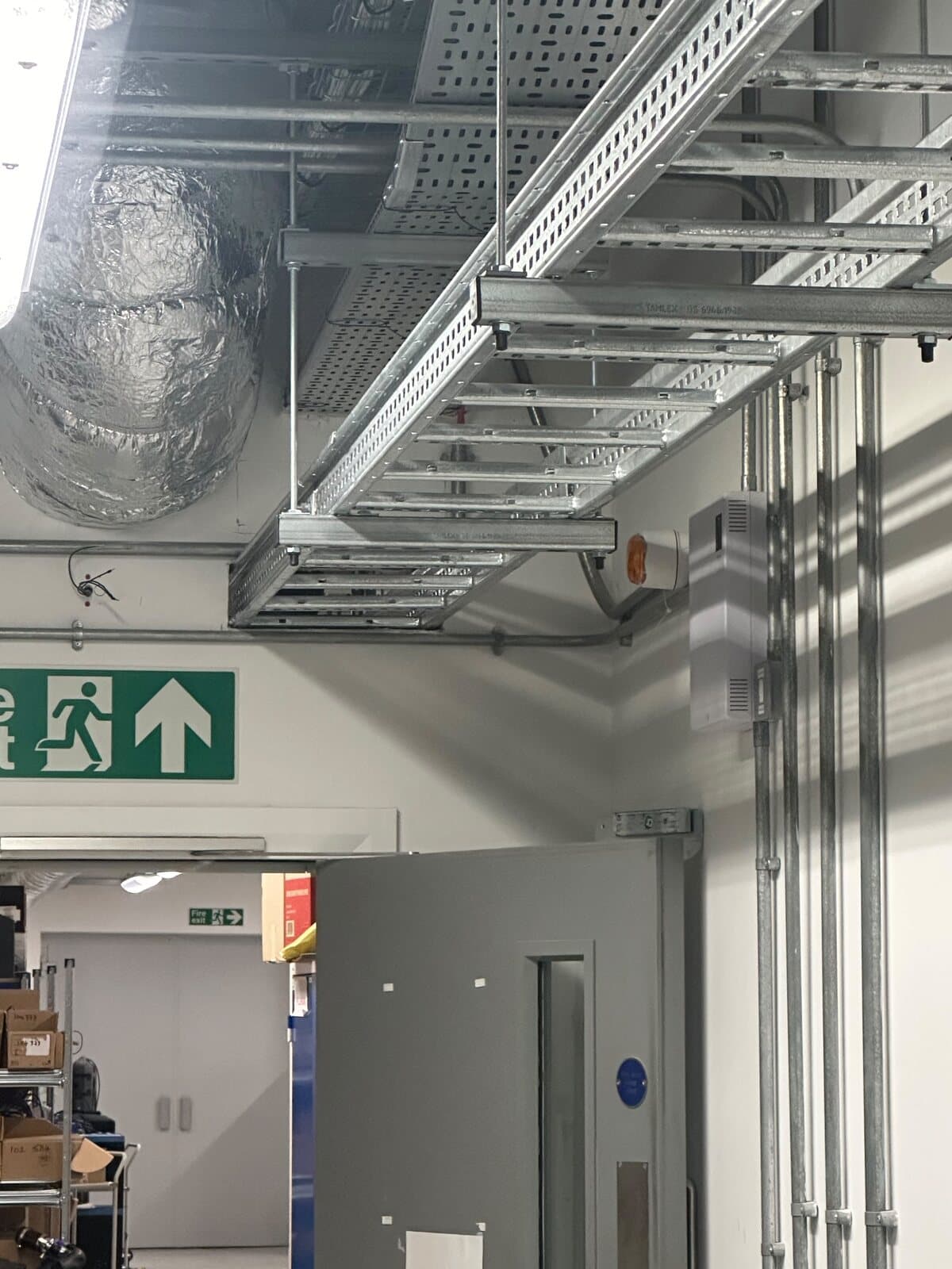 Cable tray and basket run at high level through a commercial unit, with conduit drops to each position