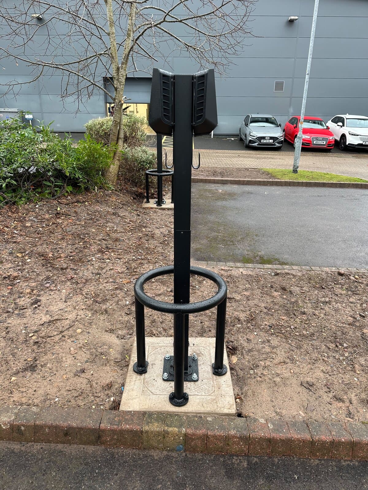 Car charging post installed with its protective hoop set into a new concrete base