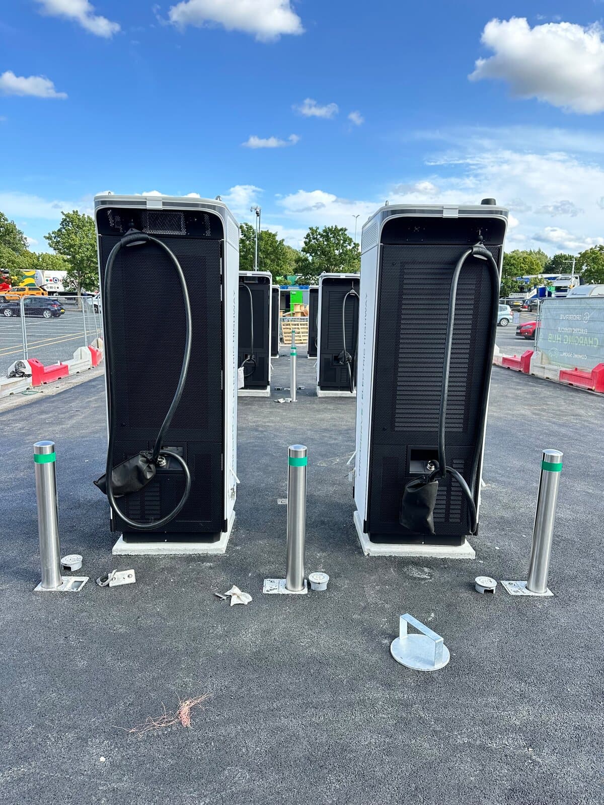 Pair of rapid car chargers being connected and commissioned on a newly surfaced charging bay
