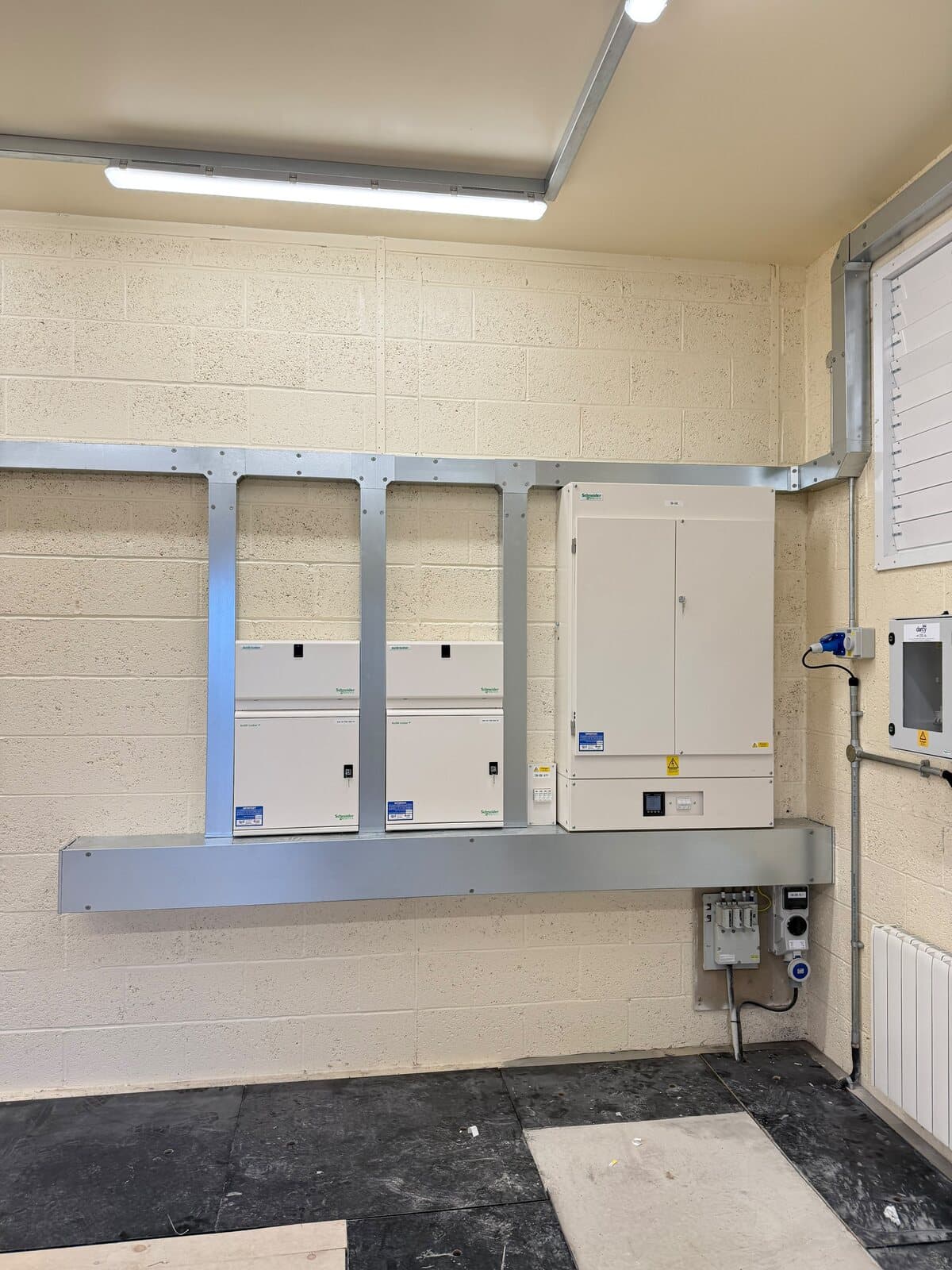 Plant room with three distribution boards mounted on a new steel frame and the supply run in overhead
