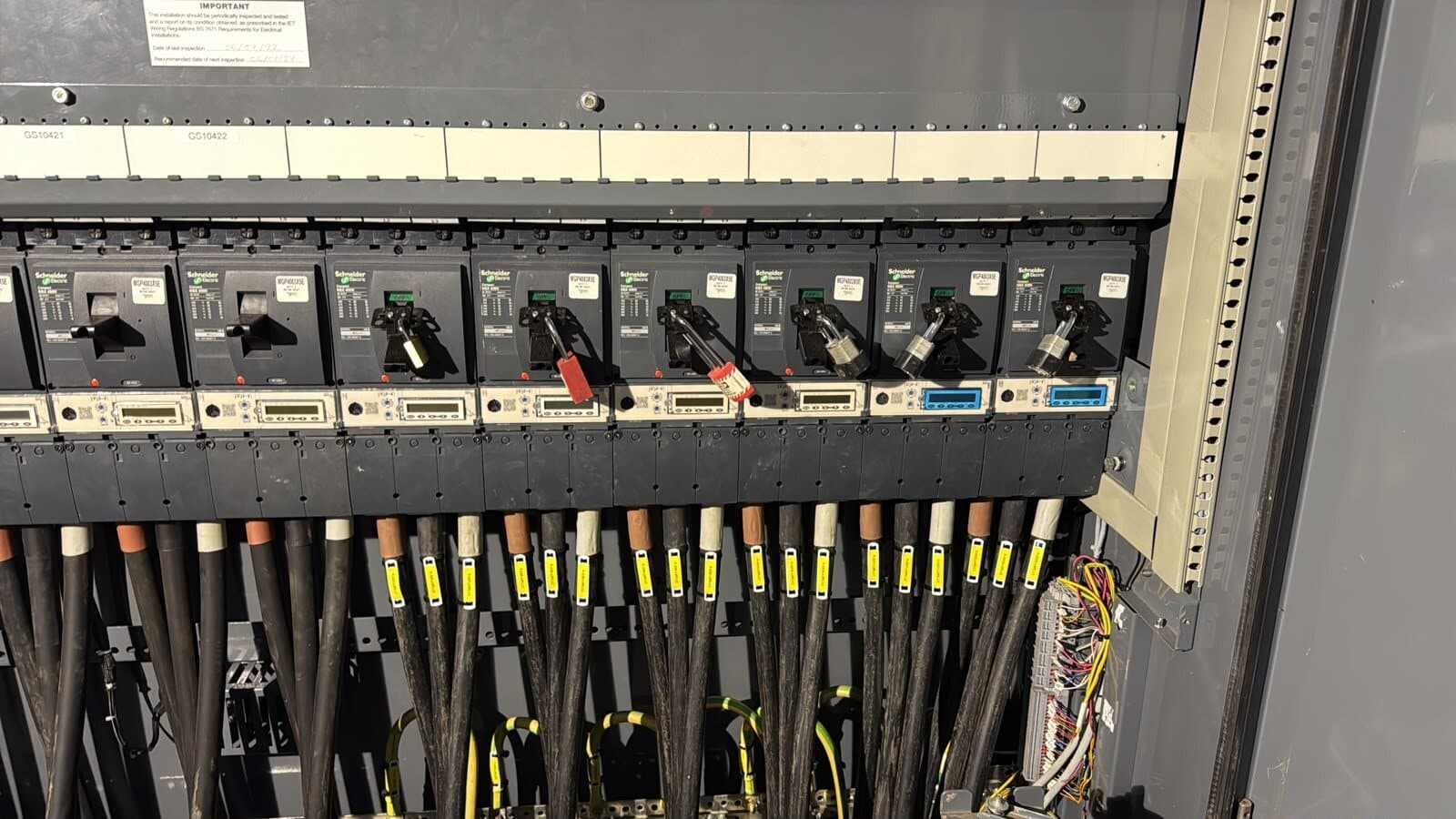 Row of fuse carriers in a switch panel with the outgoing cables dressed and labelled below