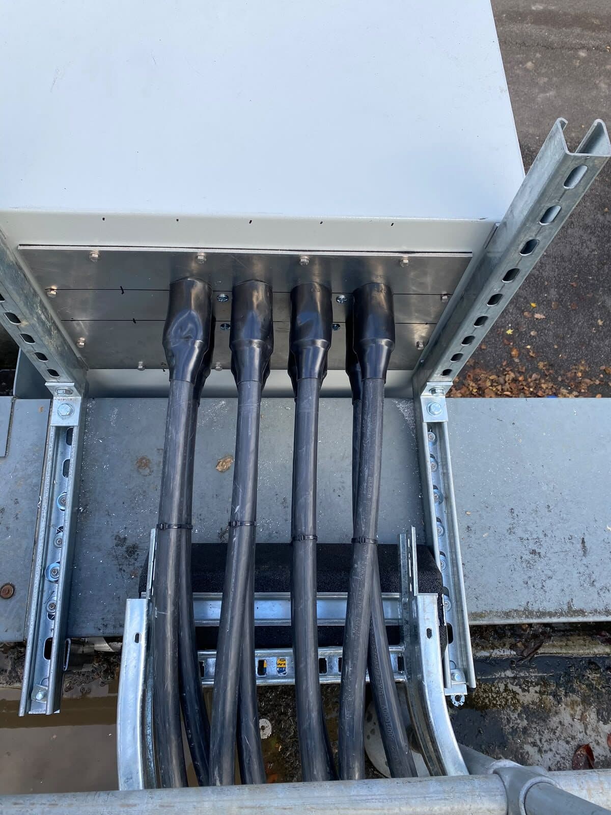 Tray dropping a group of cables neatly into the top of an outdoor enclosure