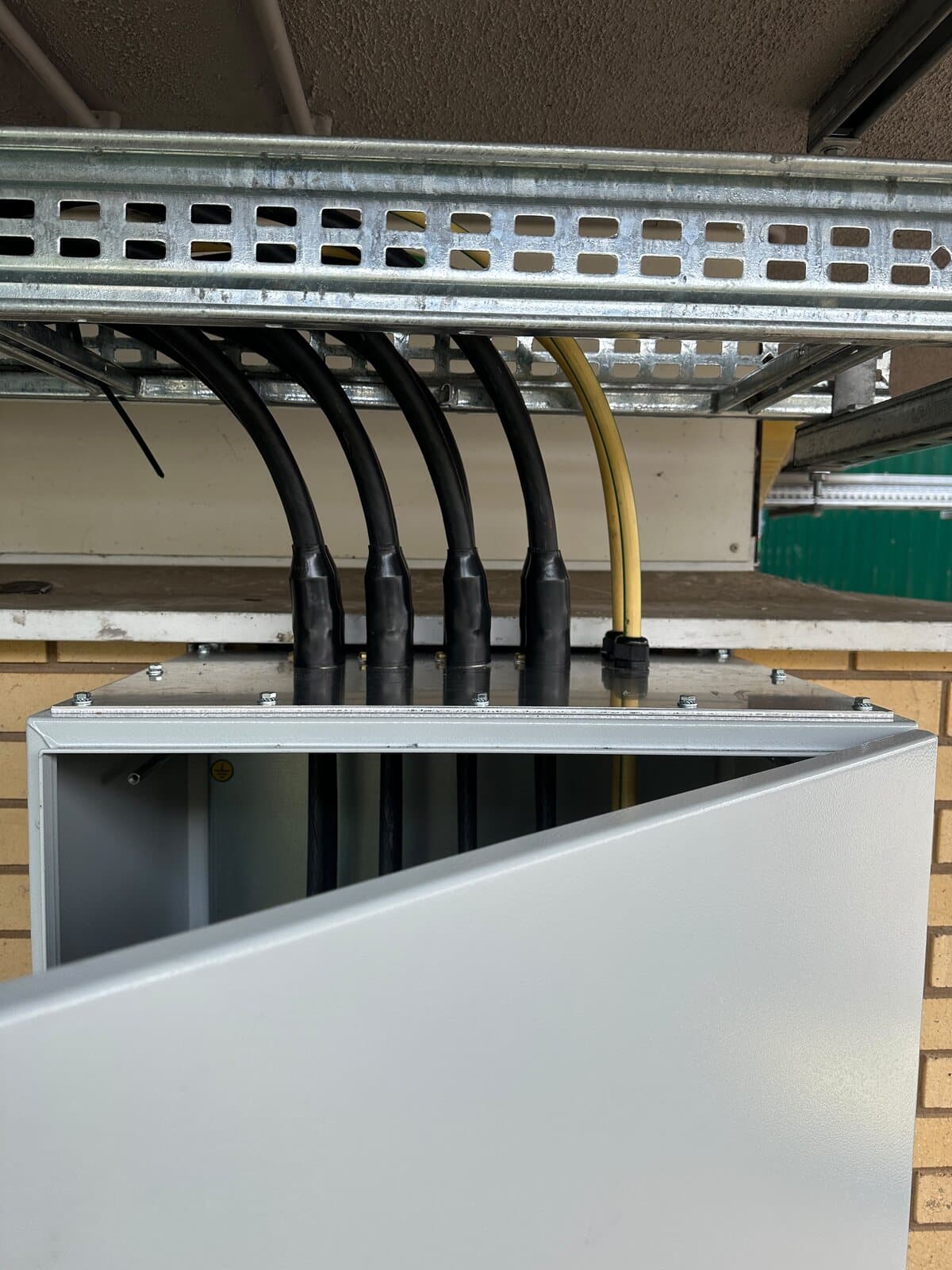 Cable tray bringing armoured cables down into a wall-mounted enclosure