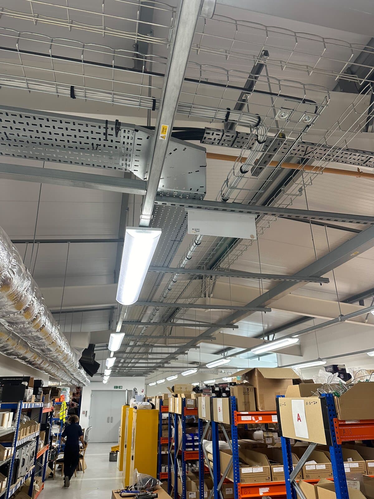 Warehouse relit with LED battens on high-level containment above the racking